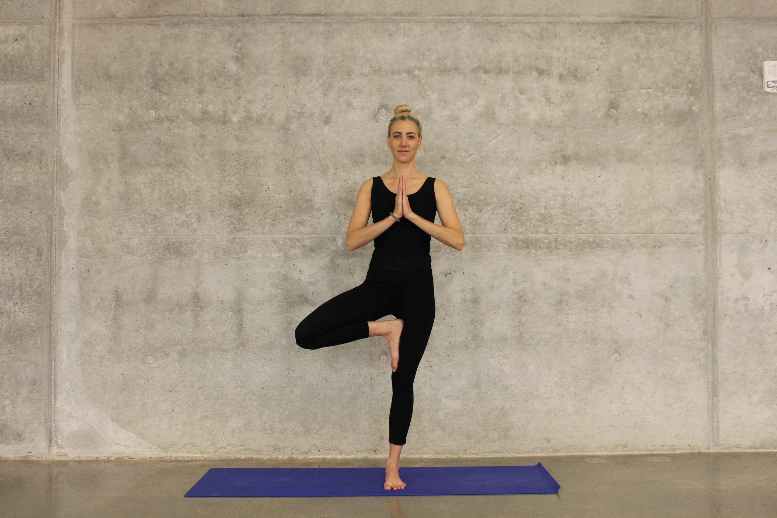 woman in black attire doing one foot stance yoga